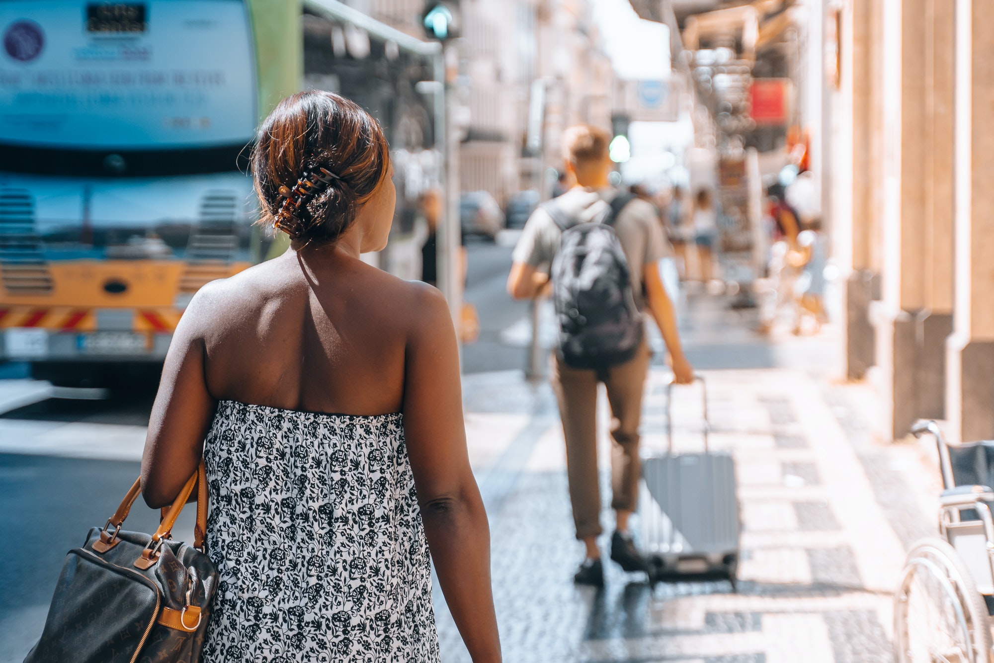 Candid fashioned young black woman from behind walking street downtown in summer.Touristic busy city